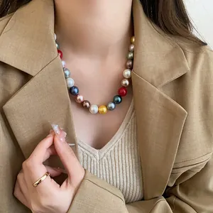 Professional close-up of a vibrant colorful pearl necklace on a model in a brown blazer.