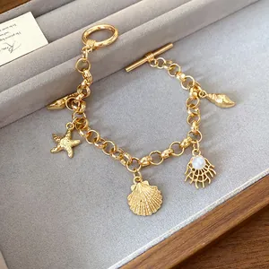 Vue détaillée d'un bracelet doré orné de pendentifs marins et d'une perle blanche