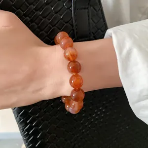 Close-up of reddish-brown agate beaded bracelet on a woman's wrist with elegant texture