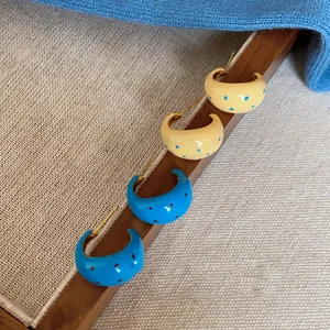 Detailed view of colorful polka dot C-shaped enamel earrings in blue and cream