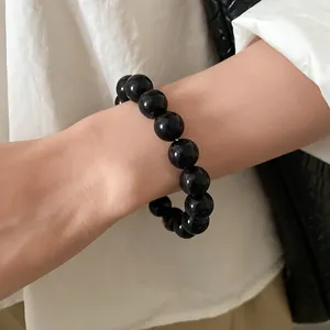Close-up detail of a minimalist black inked beaded bracelet worn elegantly on a wrist.