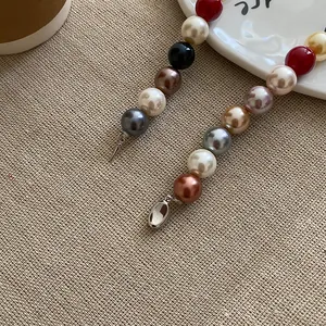 Close-up detail of a colorful round pearl beaded necklace with metallic charms on linen fabric