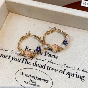 Elegant flower and pearl hoop earrings with gold-plated finish on textured display