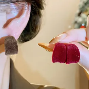 Primo piano di eleganti orecchini a forma di C in velluto floccato rosso e marrone
