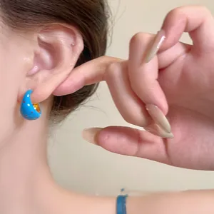 Detailed view of blue C-shape earrings with red polka dots and gold-tone lining