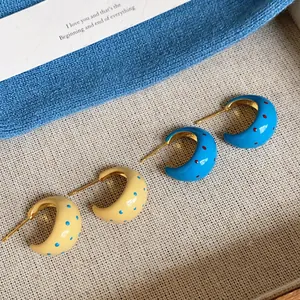 Detailed view of C-shaped enamel earrings featuring colorful polka dot patterns and gold finish