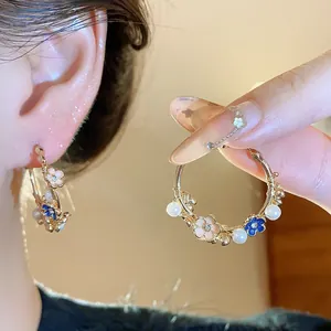 Detailed view of elegant floral hoop earrings featuring pearls and blue enamel flowers