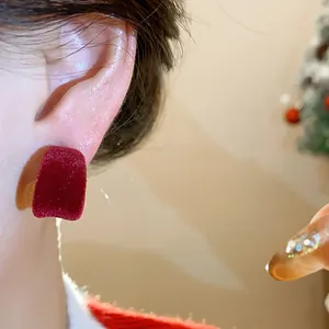 Dettaglio di un orecchino rosso floccato a forma di C indossato per la moda autunnale