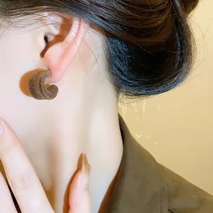 Primo piano di orecchini a forma di C floccati marroni per stile autunnale elegante