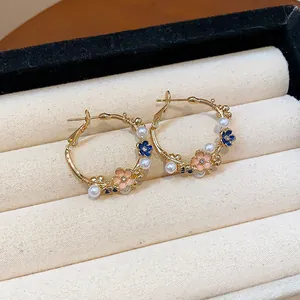 Exquisite detail of gold hoop earrings featuring pink enamel flowers and white pearls