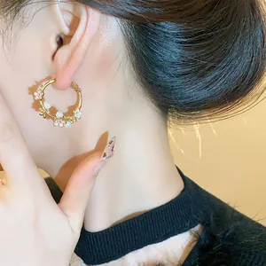 Detailed view of elegant gold-plated flower and pearl hoop earrings on model ear