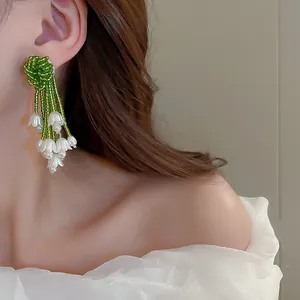 Primo piano di eleganti orecchini a nappa mughetto indossati da una modella