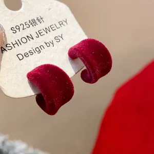 Primo piano di orecchini a forma di C floccati rossi con perno in argento.