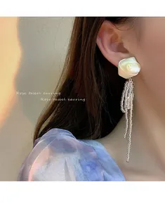 Eleganti orecchini a rosa in tessuto bianco con lunghe nappe di perline d'argento sul modello