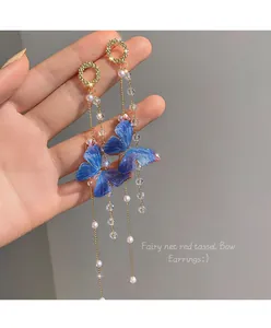 Primo piano di eleganti orecchini a nappa a farfalla blu con perle e cristalli