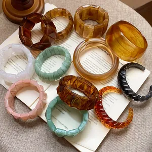 Detailed view of colorful resin and acrylic bangles arranged on a vintage book.
