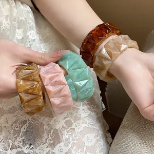 Close-up of colorful faceted acrylic bracelets with marble texture on wrist