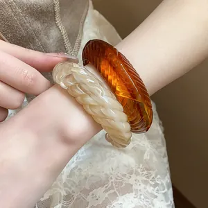 Close-up detail of twisted textured bangles in amber and marbled cream resin material