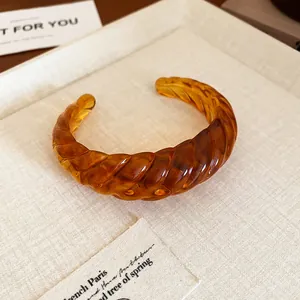 Detailed view of a vintage tortoiseshell amber resin open cuff bracelet with twisted texture