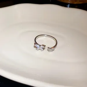 Dettaglio macro di anello aperto argentato con farfalle scintillanti in zircone