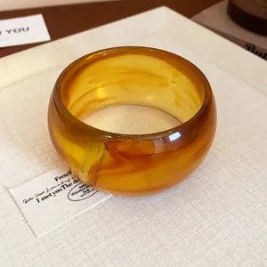 Macro view showing the translucent amber marbled texture of a chunky resin wide bangle