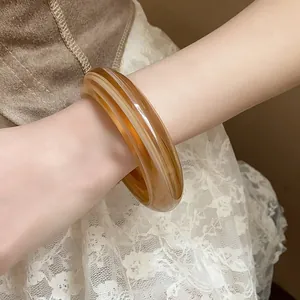 Close-up detail of a marbled amber resin oval open bangle worn elegantly on the wrist