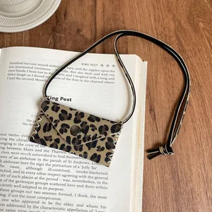 Detail shot of a vintage leopard print mini pouch necklace on an open book background.