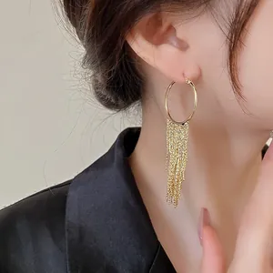 Close-up of elegant gold plated geometric hoop earrings with long tassel chains