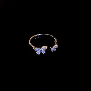 Dettaglio ravvicinato di un anello aperto a farfalla in zircone oro rosa su sfondo nero