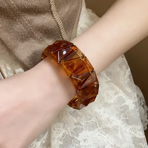 Detailed view of a stylish amber marbled geometric faceted resin bracelet worn on a wrist