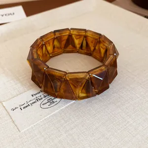 Detail view of amber tortoiseshell geometric faceted chunky bracelet on textured fabric