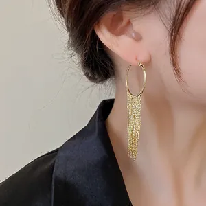 Close-up view of gold-plated geometric hoop earrings with elegant long chain tassels