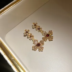Nahaufnahme von Vintage-Ohrringen mit Strassblumen und rotem Edelstein in der Mitte