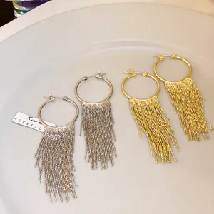 Close-up of gold and silver plated hoop earrings with long metal chain fringe