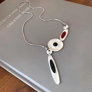 Detail of irregular metal enamel pendant necklace with black and red accents