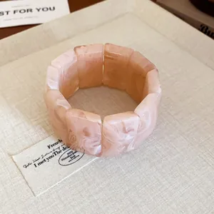 Detailed macro view of a pink marbled resin block stretch bracelet on a neutral linen background