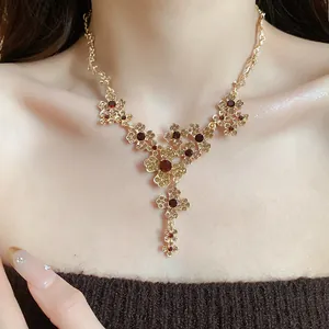 Elegante Detailaufnahme einer Vintage-Halskette mit Goldton, Blumen und roten Kristallen am Modell