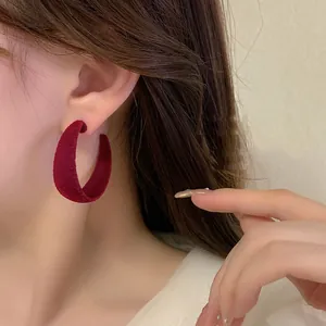Close-up detail of a burgundy velvet hoop earring worn by a model showing soft texture