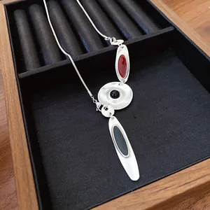 Close-up view of the irregular metal necklace with red and black enamel pendants