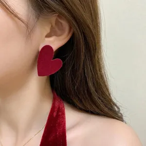 Close-up detail of a stylish red velvet heart-shaped earring worn by an Asian model