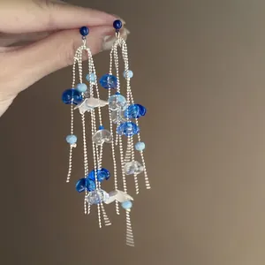Close-up of blue and white acrylic flower tassel earrings with silver needle