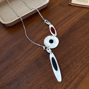Close-up view of minimalist irregular metal pendant necklace with red black enamel