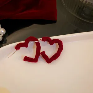 Close-up detail of elegant red velvet heart-shaped hoop earrings displayed on white tray