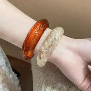 Close-up of stylish textured marble and amber resin bangles on a wrist.
