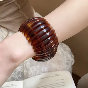 Close-up detail of an amber tortoiseshell resin open bangle with ribbed texture