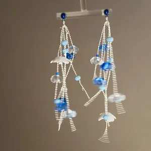 Detailed macro view of blue acrylic floral beads and long silver tassel chains on earrings