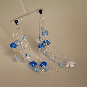 Close-up of elegant acrylic flower tassel earrings with blue beads and silver chains