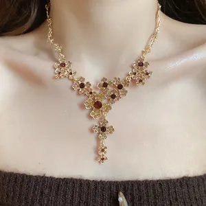 Nahaufnahme einer Halskette im Vintage-Stil mit goldenen Blumen und roten Kristallen