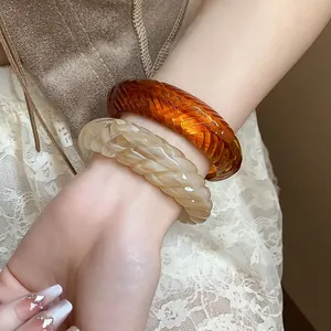 Detail view of chunky textured amber and marble resin bangles on a woman's wrist.