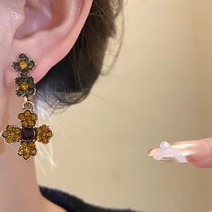 Detaillierte Nahaufnahme von Vintage-Blumen-Ohrhängern mit bernsteinfarbenen und grünen Strasssteinen